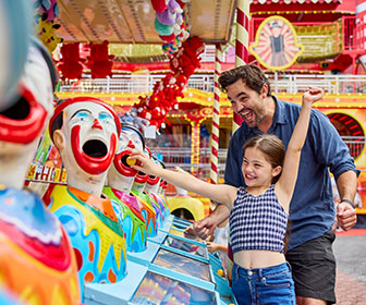 A young girl and her father laughing as they play a carnival clown-themed game together at the Sydney Royal Easter Show.