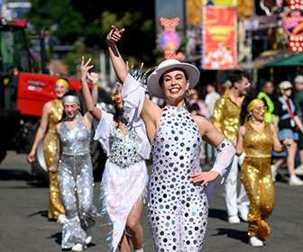 A woman performer in a polka-dot costume posing and dancing at Sydney Royal Easter Show's Street Parade.