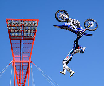A motocross rider performing a stunt mid-air with his motorbike at an Airtime Freeestyle MotoX event.