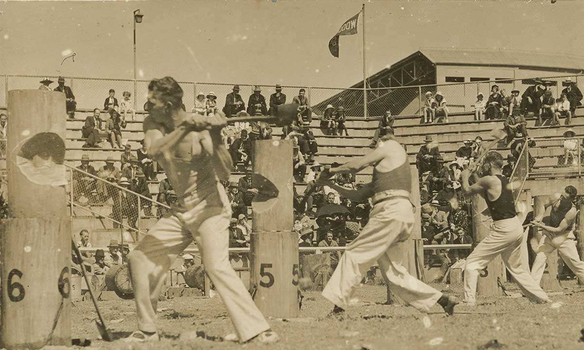 Two young girls smiling while holding colourful ice creams in front of a game stall at the Sydney Royal Easter Show.
