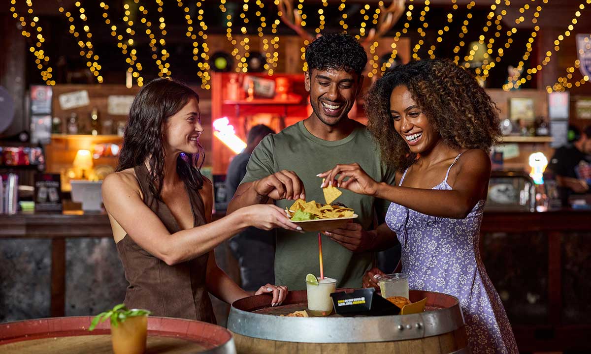 Two young girls smiling while holding colourful ice creams in front of a game stall at the Sydney Royal Easter Show.