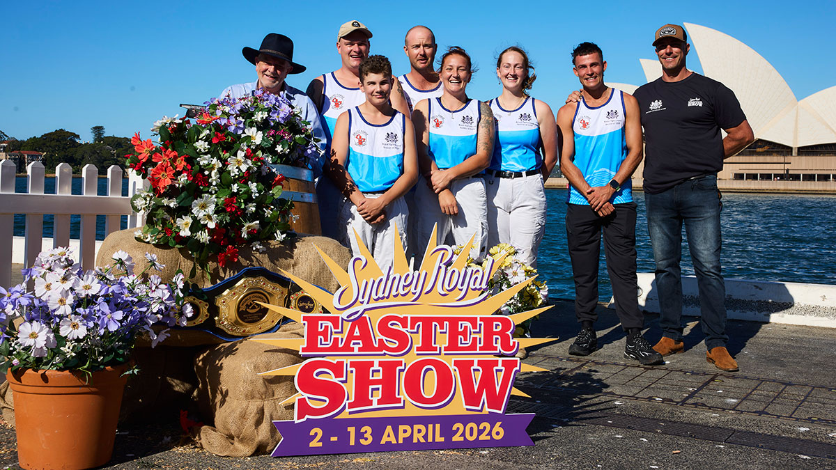 Two young girls smiling while holding colourful ice creams in front of a game stall at the Sydney Royal Easter Show.